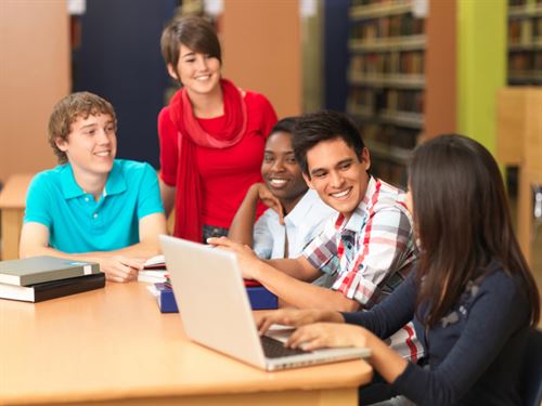 teens looking at laptop in library
